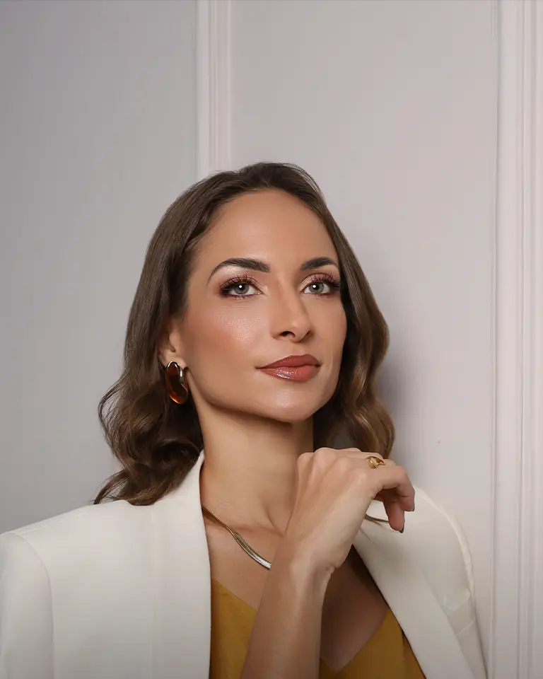 Dra. Eduarda Costa de blazer branco, com a mão apoiada no queixo